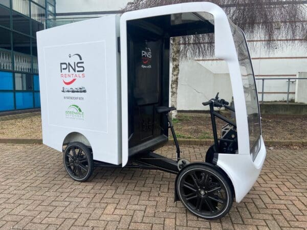 A small white cart with two wheels and a bicycle.